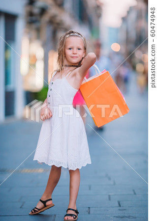 Portrait of adorable little girl walking with shopping bags outdoors in european city. Portrait of adorable little girl walking with shopping bags outdoors in european city. 60474948