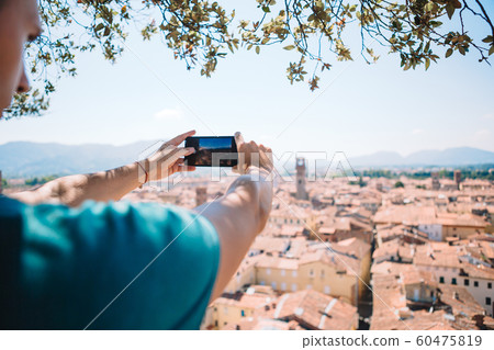 Young caucasian man making photo of european old city by mobile phone from the observation place 60475819