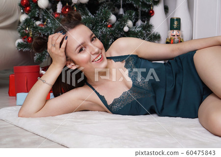 Sexy young girl in underwear is lying near gifts. Christmas interior Sexy young girl in underwear is lying near gifts. Christmas interior 60475843