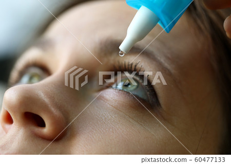 Female putting liquid drops in her eye solving vision problem Female putting liquid drops in her eye solving vision problem 60477133