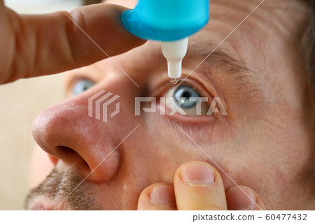 Male hand putting liquid drops in his eye Male hand putting liquid drops in his eye 60477432