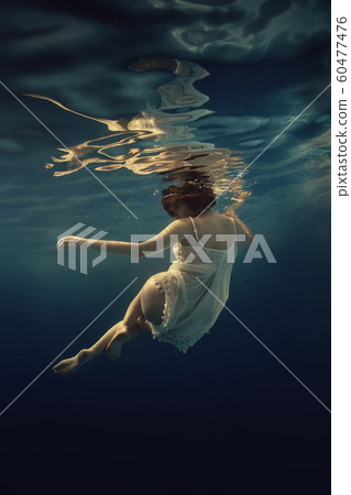 Girl in a white suit swims underwater Girl in a white suit swims underwater 60477476