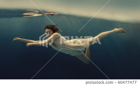 Girl in a white suit swims underwater Girl in a white suit swims underwater 60477477