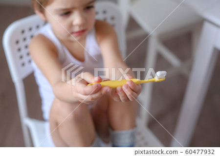 Boy cleans his teeth in the morning and plays with a toothbrush 60477932
