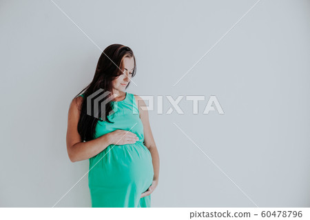 a pregnant woman is standing at the wall next to the window a pregnant woman is standing at the wall next to the window 60478796