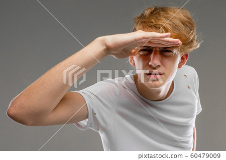Young caucasian man in white t-shirt posing and gesticulating on camera isolated on grey background 60479009