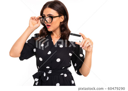 Young caucasian girl with delightful smile, in black and white dress in peas works with a card Young caucasian girl with delightful smile, in black and white dress in peas works with a card 60479290