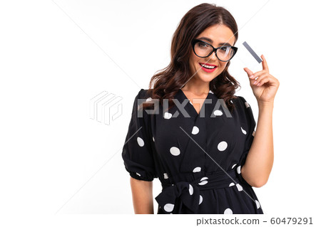 smilingbrunette in glasses holds a credit card with a mockup on a white background with copy space 60479291