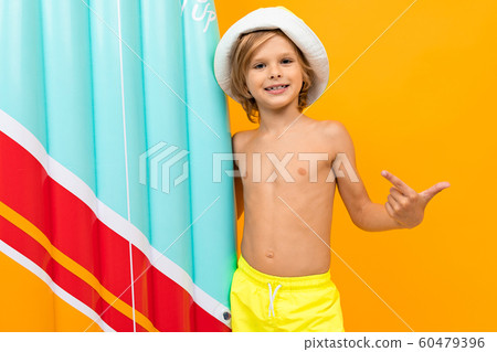 attractive European blond boy in a summer panama with an inflatable swimming board on a yellow attractive European blond boy in a summer panama with an inflatable swimming board on a yellow 60479396