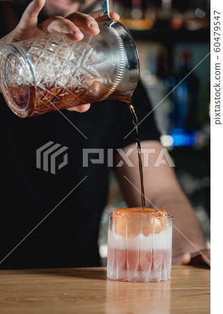 Boulevardie cocktail on a bar desk. Bartender pouring alcohol Boulevardie cocktail on a bar desk. Bartender pouring alcohol 60479547
