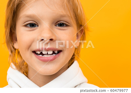 attractive smiling blond boy in a white hoodie on an orange background close-up 60479977