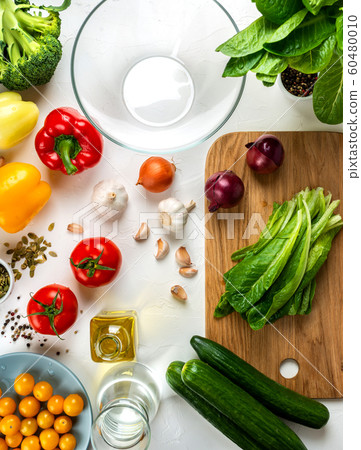 Romaine lettuce on the board and Different vegetables and spices on the table. Ingredients for cook salad. Healthy diet vegan food concept. Top view. 60480010