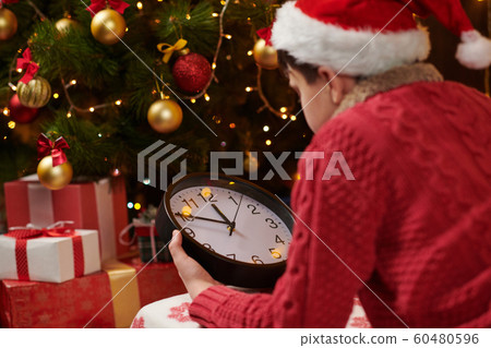 Teen boy waiting for Santa and watching the clock, Teen boy waiting for Santa and watching the clock, 60480596