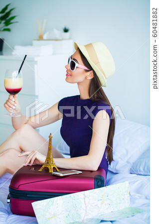 Vacation. Woman Who is Preparing for Rest. Young Beautiful Girl Sits on the Bed and Holds in the Hands Cocktail. Portrait of a Smiling Woman. Happy Girl Goes On Vacation Vacation. Woman Who is Preparing for Rest. Young Beautiful Girl Sits on the Bed and Holds in the Hands Cocktail. Portrait of a Smiling Woman. Happy Girl Goes On Vacation 60481882