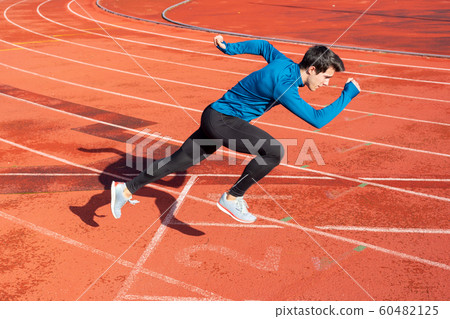 Runner starting his sprint on running track in a stadium.  60482125