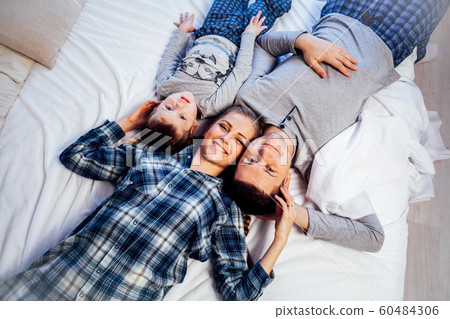 mom dad and son in the morning lying on the bed at home in a good mood 60484306