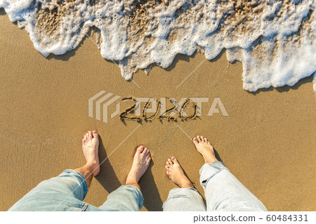 Top view legs of a couple on sandy beach year 2020 and wave 60484331