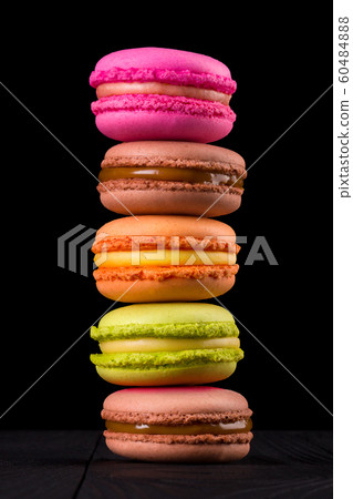 Row of french colorful macaroons or heap on wooden table isolated on black 60484888