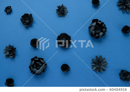 Black paper flowers on blue background. Cut from 60484916