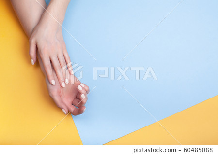 Beautiful female hands with a classic matte manicure on a blue-yellow background Beautiful female hands with a classic matte manicure on a blue-yellow background 60485088