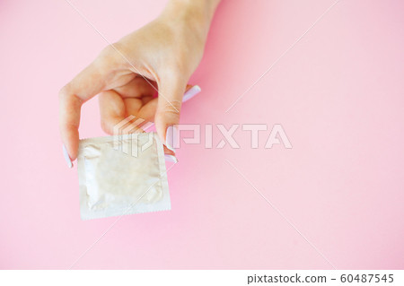 Contraception. Birth Control Pills and an unwrapped Condom. Colored Pills And Capsule On Pink Background. Pharmacy Theme, Capsule Pills With Medicine Antibiotic in Packages 60487545