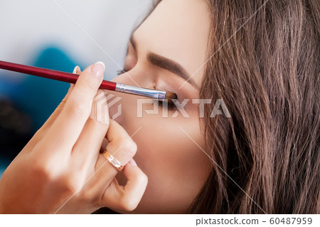make-up artist doing make-up girl in the salon, beauty concept 60487959