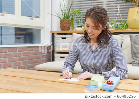 Young woman wrapping a gift by writing a message card 60496250