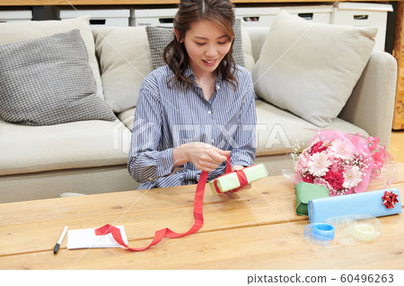 通過寫留言卡包裝禮物的年輕女子 通過寫留言卡包裝禮物的年輕女子 60496263
