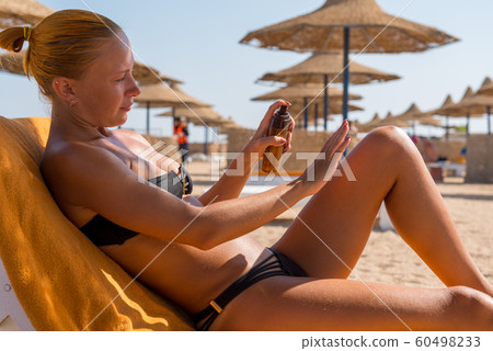 Sensuous slim woman applying suntan oil Sensuous slim woman applying suntan oil 60498233