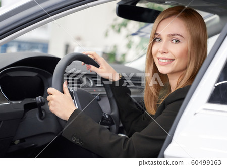 Female customer of auto salon sitting in white car Female customer of auto salon sitting in white car 60499163