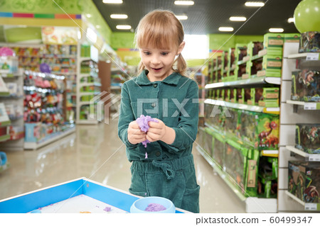 Positive little girl sculpting with plasticine in toy store Positive little girl sculpting with plasticine in toy store 60499347