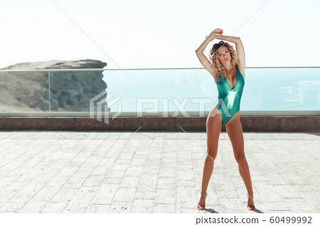 A woman is a young model with long beautiful legs and loose hair in a bikini swimsuit 60499992