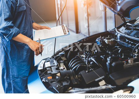 Car mechanic holding clipboard and checking to 60500960