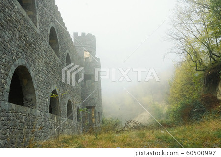 Medieval castle and fort with arch windows in misty and foggy morning on a hill. Medieval castle and fort with arch windows in misty and foggy morning on a hill. 60500997