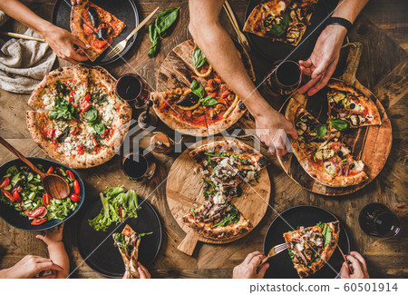 People eating different kinds of pizza, salad and 60501914