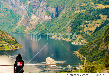 Tourist over fjord wearing norwegian flag clothing Tourist over fjord wearing norwegian flag clothing 60502145