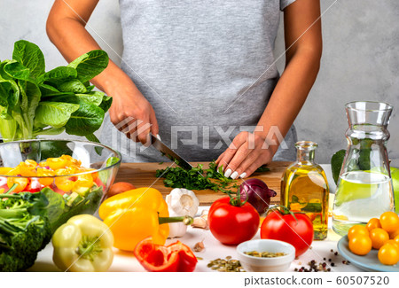 Woman cuts greens and cooking salad in the kitchen. Healthy diet concept. 60507520