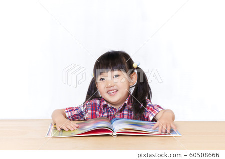 Little girl reading a book in front of a white background. Infant, education, reading, learning, growth, childcare image 60508666