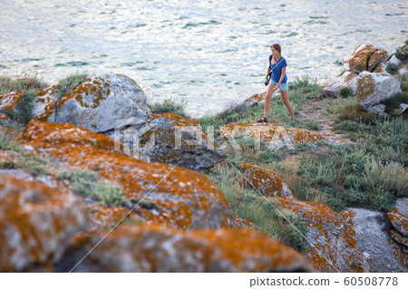 Happy young traveler with walking by footpath trail at mountains near the sea Happy young traveler with walking by footpath trail at mountains near the sea 60508778