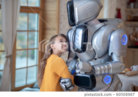 Cute girl in orange shirt feeling comfortable with her house robot Cute girl in orange shirt feeling comfortable with her house robot 60508987