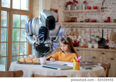 Robot teacher looking attentively how the girl writing 60509448