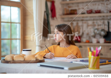 Cute girl in orange shirt looking thoughtful 60509488