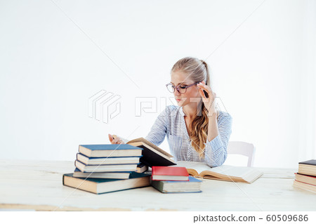 female teacher sitting at a table of many books Office female teacher sitting at a table of many books Office 60509686