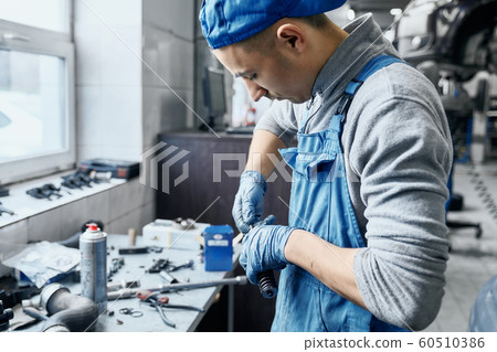 Repairman in car service working with small details on table 60510386