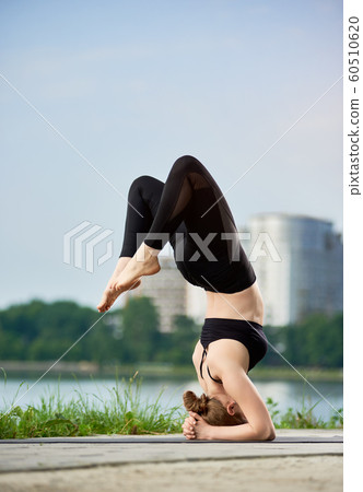 Young woman practicing yoga at city lake 60510620