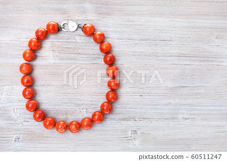 top view of red coral necklace on gray wood board 60511247