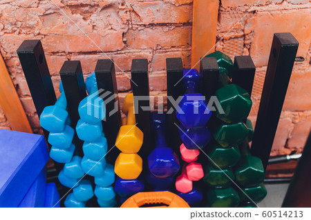 Receding row of weights lined up in a gym waiting for clients with focus to the third and fourth dumbbells in the row. 60514213