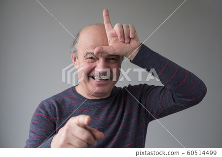 Man showing sign over forehead and smiling broadly, bragging about victory 60514499