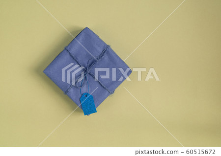 paper wrapped gift with blue tag yellow background 60515672