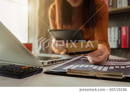 Women use credit cards to pay through tablet and laptop in office. Women use credit cards to pay through tablet and laptop in office. 60519286